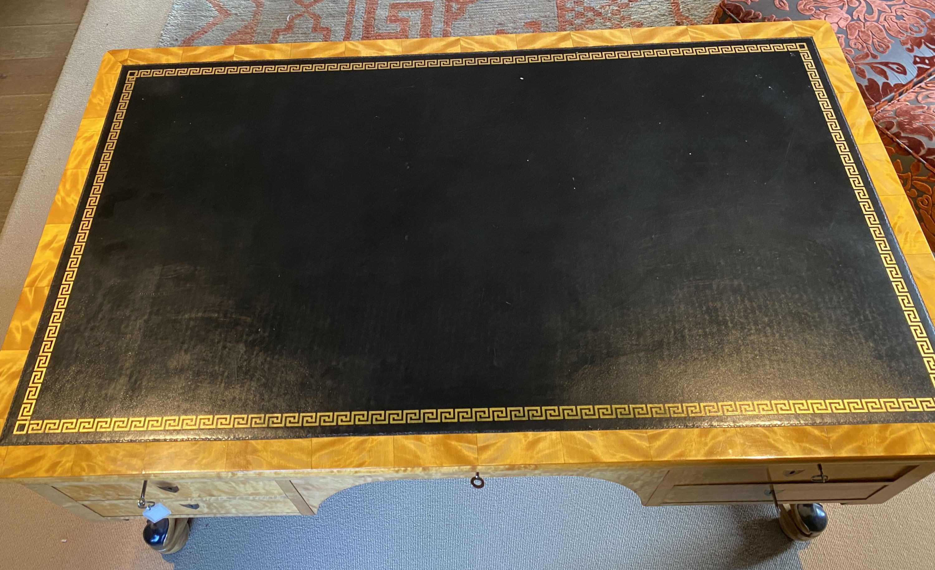 A Biedermeier style maple desk, with black leather skiver and seven drawers, on ebonised scroll legs with H stretcher, width 155cm depth 91cm height 76cm